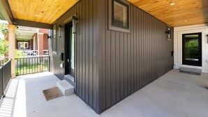 Ein Gebäude mit Holzbalkendecke, dunkler Außenwand und einer schwarzen Tür.