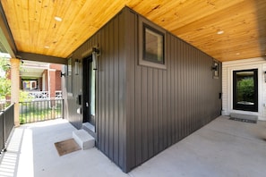 A building with a wooden ceiling, a dark exterior wall, and a black door.