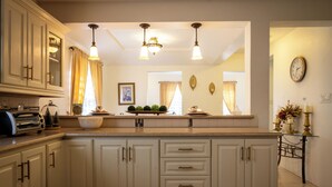 A kitchen with a central island, white cabinetry, a toaster, and a clock on the wall. - Exquisite 3-bedroom house in peaceful Mount Pleasant, St. John’s with AC comfort (St. John’s)