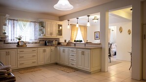 A spacious kitchen with white cabinetry, a large island, and pendant lighting. - Exquisite 3-bedroom house in peaceful Mount Pleasant, St. John’s with AC comfort (St. John’s)