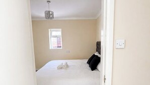 Een slaapkamer met een bed, een raam, een lamp en een deur.