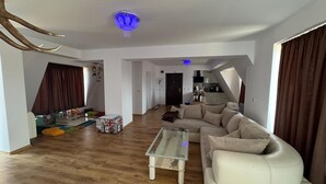 A modern living room with a sofa, a glass coffee table, and a ceiling light fixture. - Apartment Sleeps 6- Free Parking- Balcony (Казанлък)