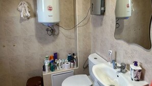 A bathroom with a toilet, sink, mirror, towel rack, and a wall-mounted heater. - Apartment Sleeps 6- Free Parking- Balcony (Казанлък)