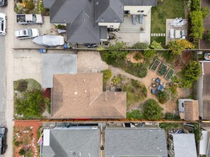 Luchtbeeld van een woongebied met een huis met schuin dak, een tuin met diverse planten en een klein terras.