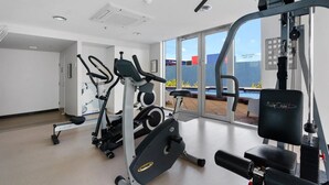 Un gimnasio con máquinas de cardio, equipo de levantamiento de pesas y vistas a una piscina.