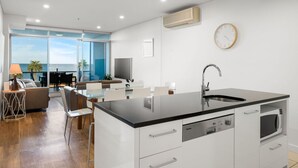 Una cocina moderna con una isla grande, un comedor con vistas y una sala de estar con sofá y televisor.