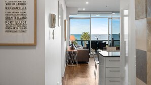 Una cocina moderna con vista al océano, un comedor con mesa y sillas, y un cartel en la pared que enumera lugares cercanos.