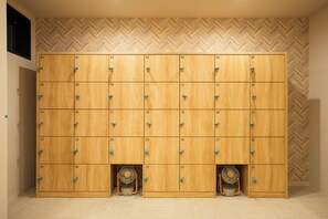 A row of wooden lockers with numbered compartments, some with fans installed.