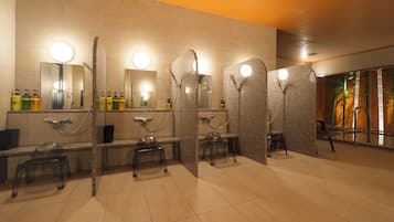 Une salle de bain moderne dotée de plusieurs lavabos, de miroirs et d’un espace douche.