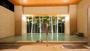 A spa area with a pool, wooden ceiling, and bamboo plants.