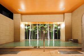 Ett spaområde med en pool, ett träpanelat tak och bambuväxter.