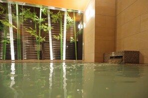 A spa area with a large indoor pool, bamboo plants, and a stone bench.
