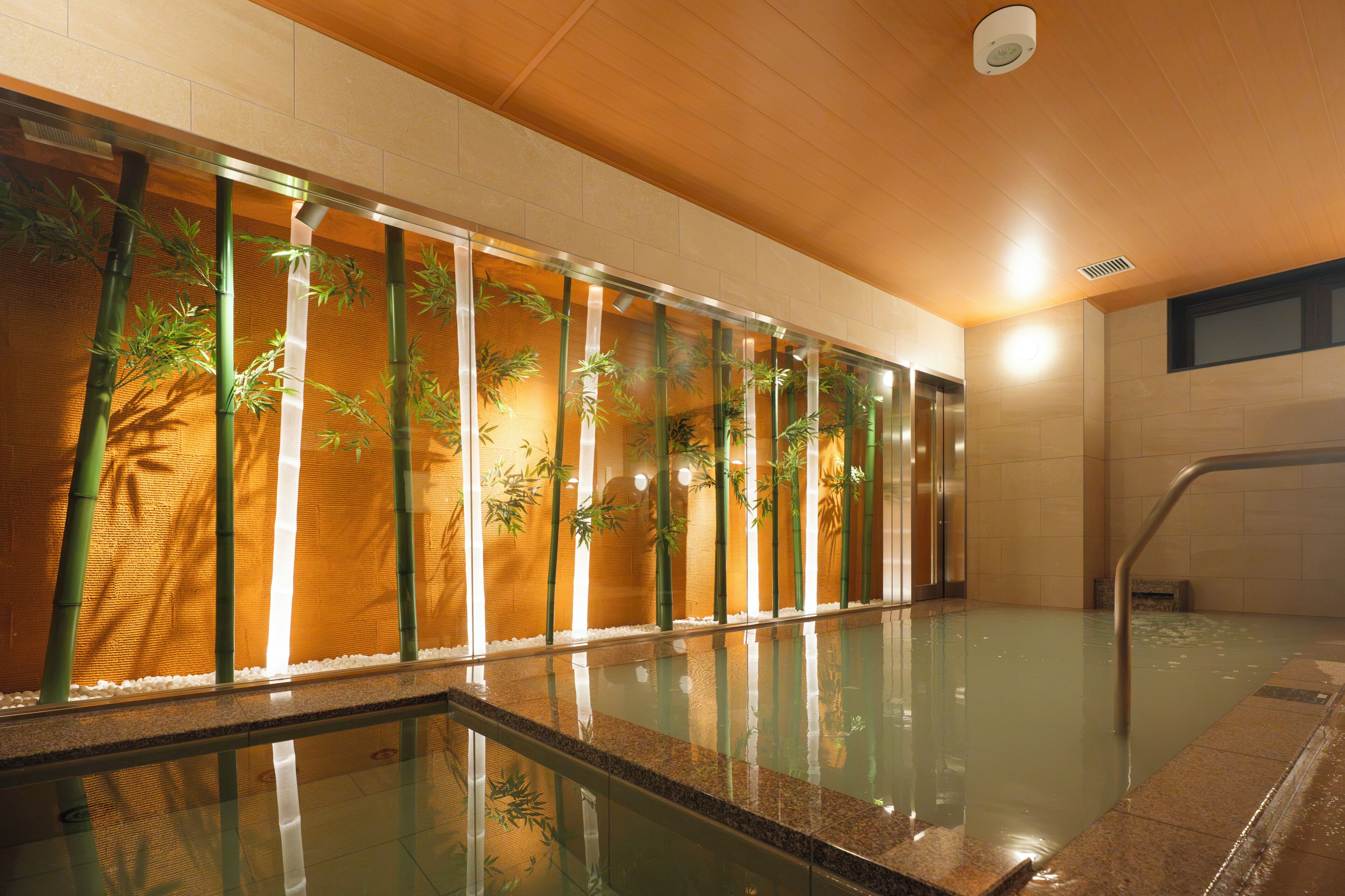Uma piscina com paredes de vidro e plantas de bambu.