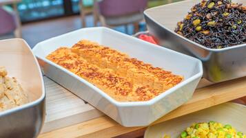 A buffet table with various dishes, including a casserole, a salad, and a dish with black rice.