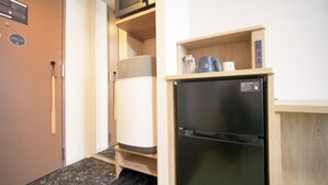 A compact kitchenette with a microwave, kettle, and refrigerator.