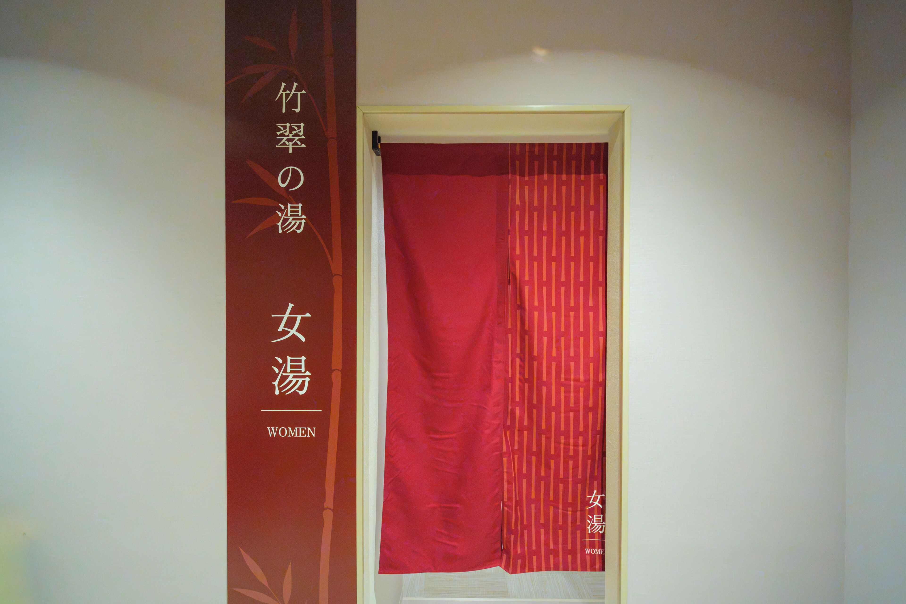 Una stanza con una tenda rossa e un cartello verticale con testo giapponese.