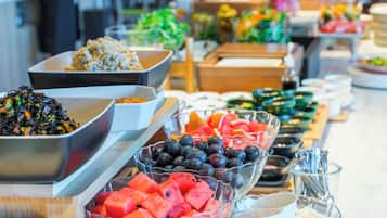 A buffet with various food items including fruits, vegetables, and grains.