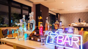 A bar area with various bottles and a neon sign that reads 'LYBAR'.