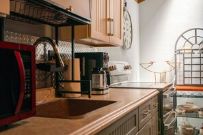 Eine Küche mit Spüle, Kaffeemaschine, Mikrowelle und einer Uhr an der Wand.