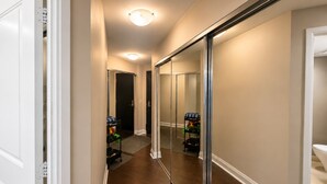 A hallway with a mirrored closet door, wooden flooring, and a ceiling light fixture. - Sunset Skyline Corner Suite in Downtown Toronto with Stunning CN Tower View! (Toronto)