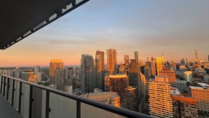 A cityscape with high-rise buildings, a clear sky, and a balcony railing. - Sunset Skyline Corner Suite in Downtown Toronto with Stunning CN Tower View! (Toronto)