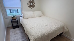 Et soveværelse med seng, et lille bord, et vindue med udsigt og en loftlampe.