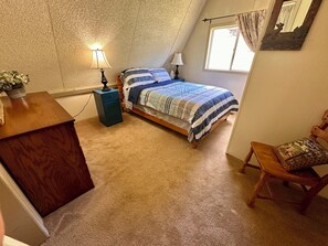 A bedroom with a bed, bedside tables, a chair, a dresser, and a window.