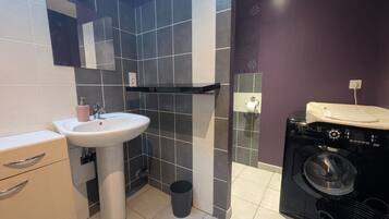 A bathroom with a sink, mirror, towel rack, and a washing machine.