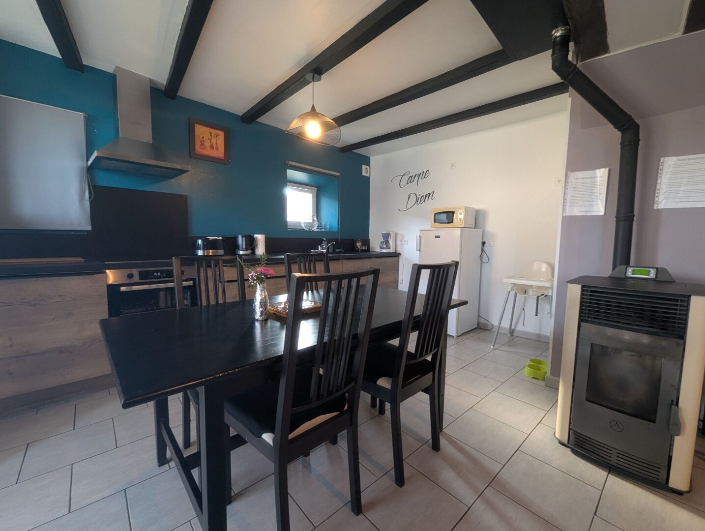 Een moderne keuken met een eettafel, stoelen, een magnetron en een koelkast.