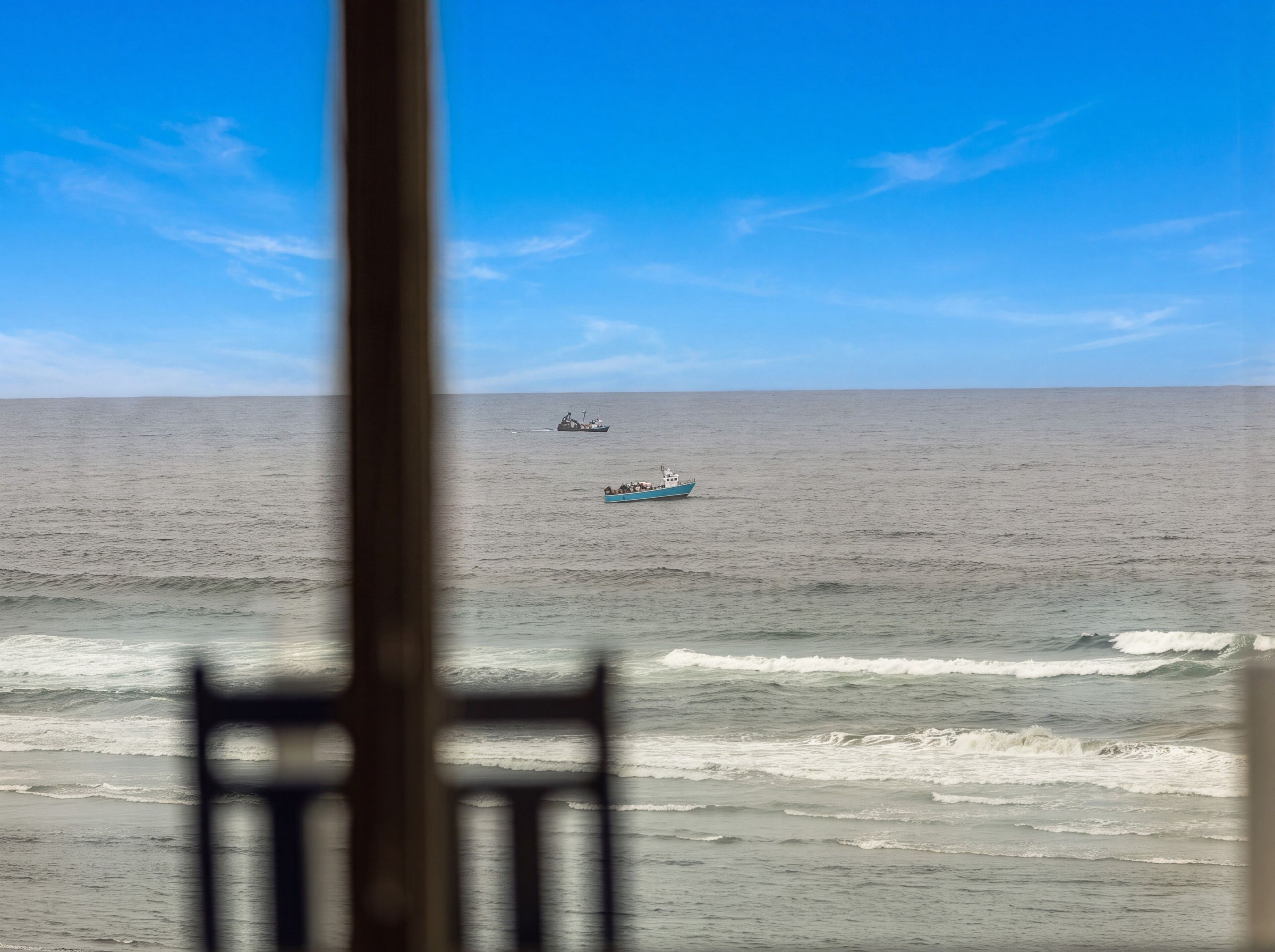A view of the ocean with a boat and a larger ship in the distance.