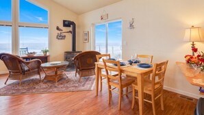 Un coin repas avec vue sur l’océan, une cheminée et une table dressée pour deux personnes.
