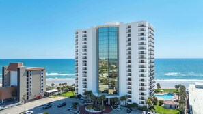 A high-rise hotel with a glass facade, a pool, and a view of the ocean. - Floridian Paradise - Luxury Oceanfront Condo (Daytona Beach Shores)