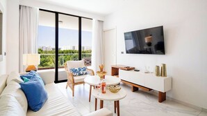 Ein modernes Wohnzimmer mit einer Couch, einem Esstisch, einem Fernseher und einem Balkon mit Blick.