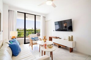 Ein modernes Wohnzimmer mit einer Couch, einem Esstisch, einem Fernseher und einem Balkon mit Blick.