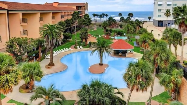 Et resort med swimmingpool, palmer og havudsigt.