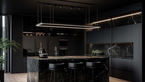 Una cocina moderna con una isla de mármol, taburetes negros y lámparas colgantes.