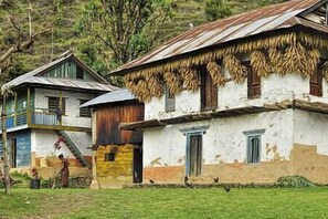Ein rustikales Gebäude mit einem Strohdach, einer Holztür und einem kleinen Balkon.