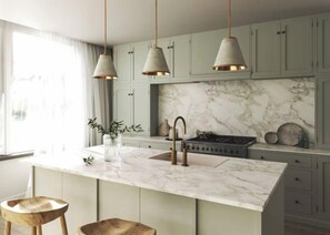 A kitchen with a marble island, pendant lights, and light-colored cabinets. - Charming 4-Bedroom Retreat in Carlton, VIC (Brisbane)