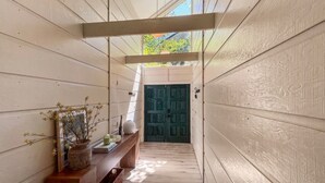 Um corredor estreito com paredes de madeira e uma porta verde escura no final.