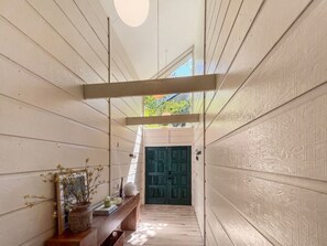 A narrow hallway with wooden walls and a dark green door at the end. - Payette Lake Retreat | Dock, Beach, Room for Toys! (McCall)