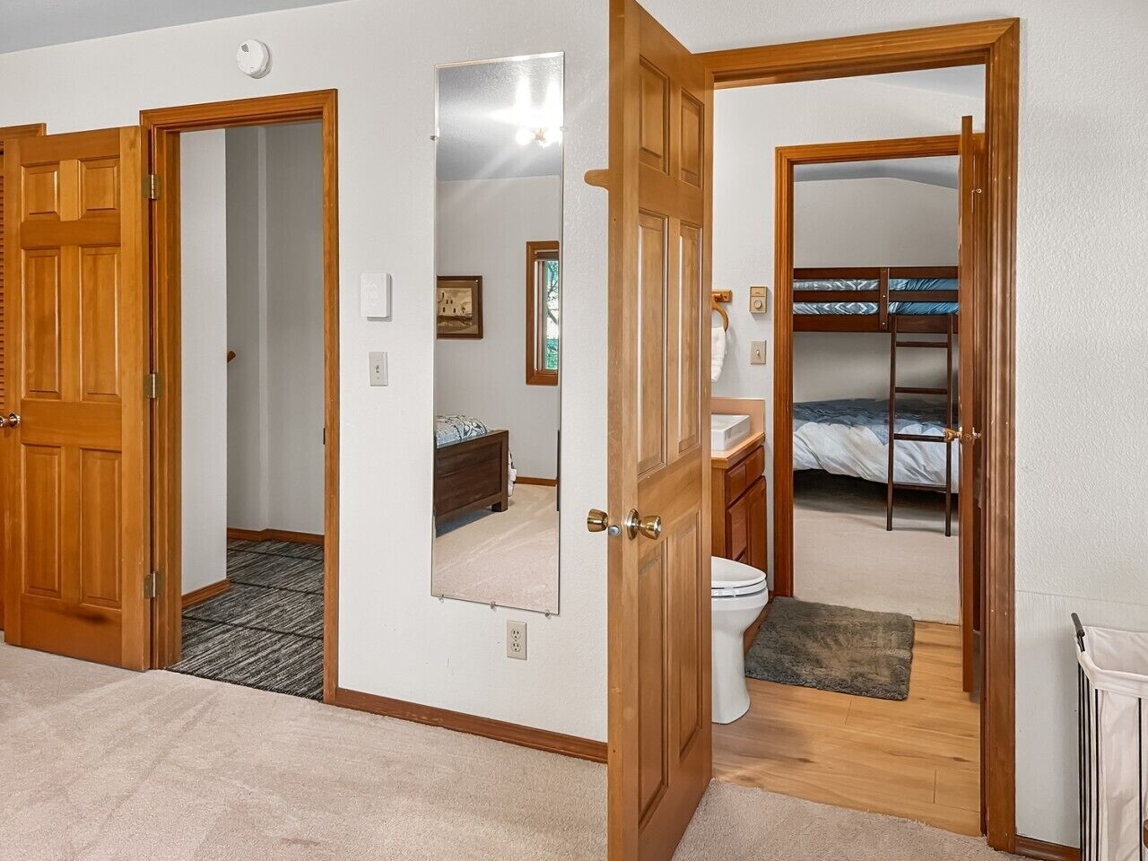 Une pièce avec une porte en bois, un miroir, un lit, des toilettes et un petit tapis.