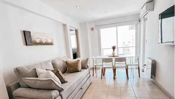 A modern living room with a sofa, a dining table, and chairs. - Dpto ubicación ideal para 6 (Salta)