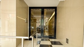 Un interno moderno con pavimento a scacchi, ringhiera in metallo e porta in vetro dotata di inferriate.