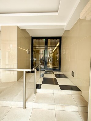 Un intérieur moderne avec un sol à carreaux, une rambarde en métal et une porte en verre avec des barreaux en métal.