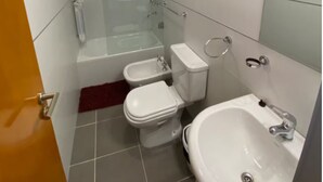 Een badkamer met een douchecabine, een bad, een toilet en een wastafel.