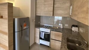 Een moderne keuken met een roestvrijstalen koelkast, een gasfornuis, houten kastjes en een granieten aanrecht.