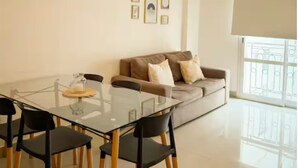 A modern living room with a glass dining table, black chairs, a sofa with cushions, a hanging light fixture, and framed pictures on the wall. - Dpto con excelente ubicación en Salta, Capital (Salta)