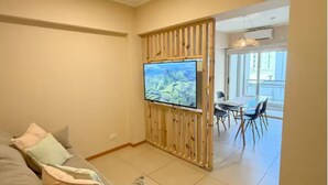 Ein Wohnzimmer mit Sofa, Fernseher und Essbereich mit Stühlen.