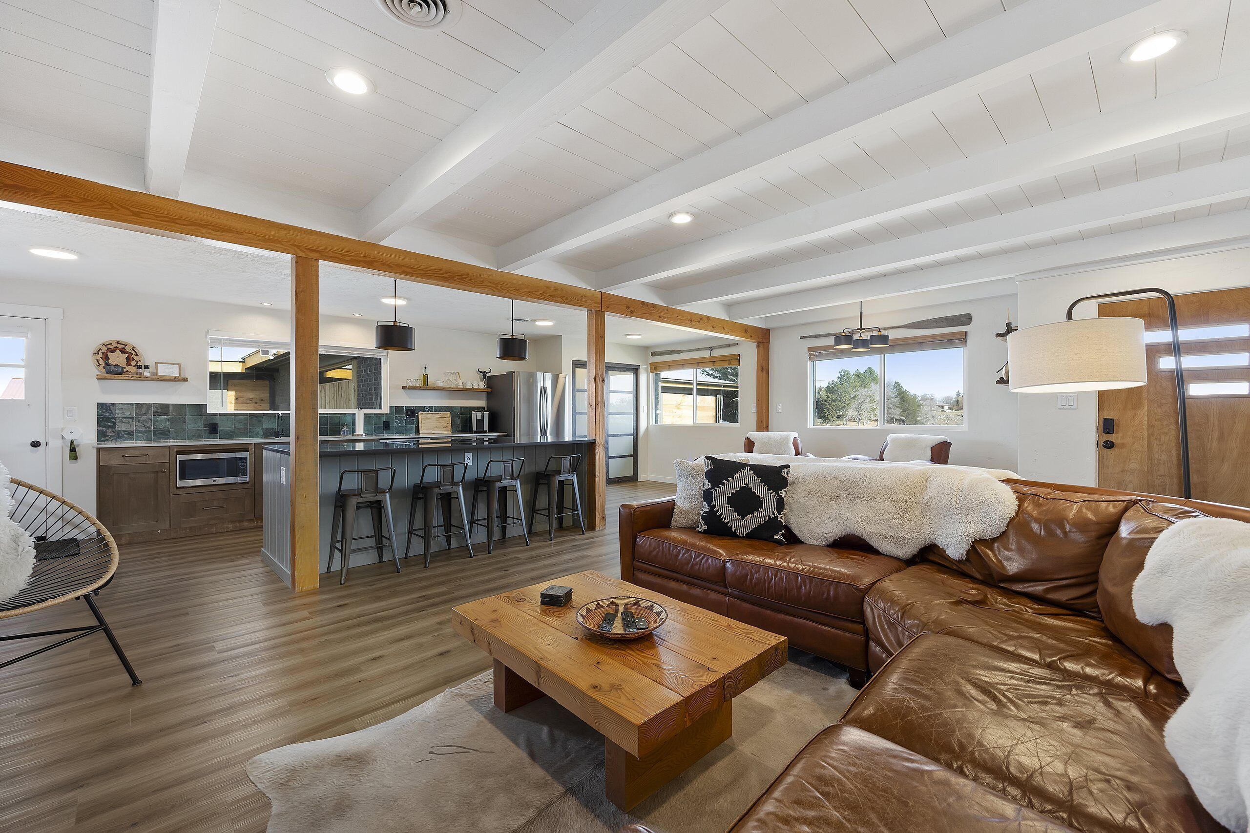 A spacious living area with a leather sofa, a wooden coffee table, and a kitchen in the background.