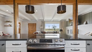 Une cuisine moderne dotée d’un îlot central, d’appareils électroménagers en acier inoxydable et offrant une vue sur l’extérieur.